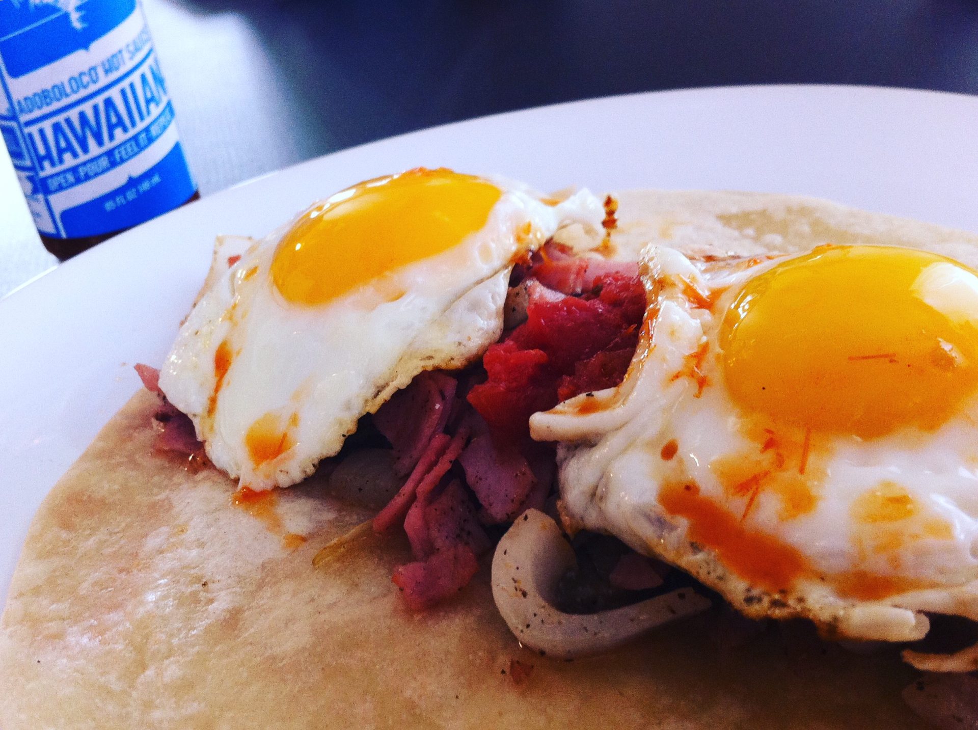 Breakfast Taco with Ham, Onions and Sunnyside up Eggs in a grilled soft tortilla slathered in Adoboloco Hawaiian Chili Pepper Water
