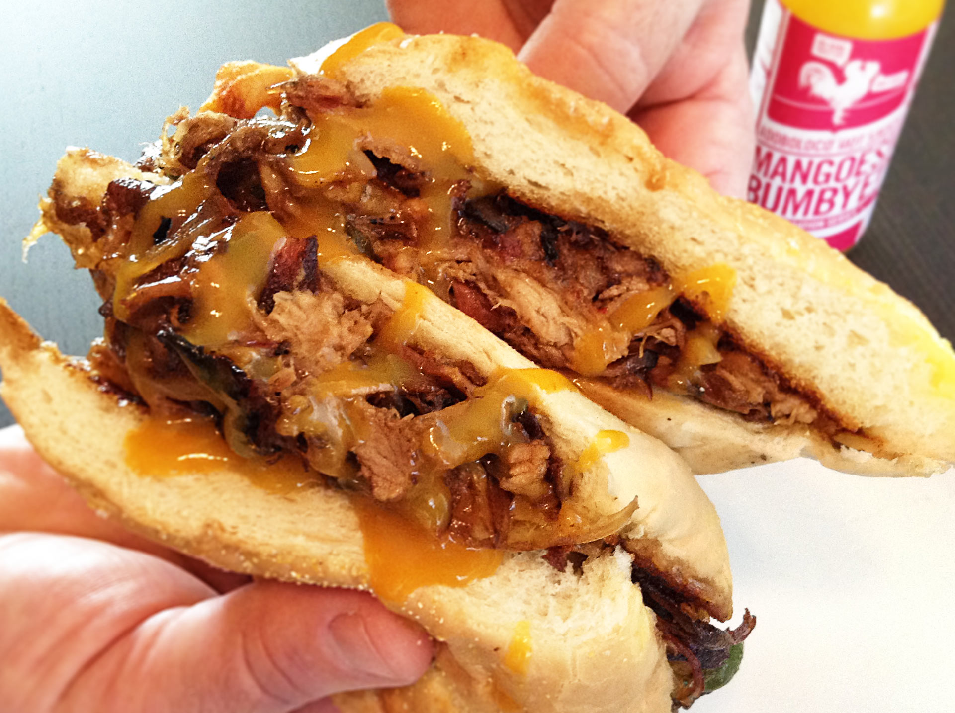 Pono Farms Fine Meats Shreadded Pork Cheessteak with sliced Jalapeno and Adoboloco Mango Habanero Hot Sauce